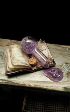 an old book and some glass beads on a wooden table with a black wall in the background