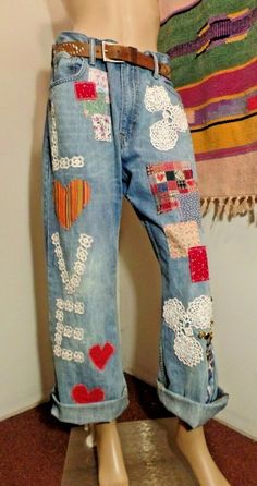 a mannequin wearing jeans with patches and hearts on it's sides, in front of a wall