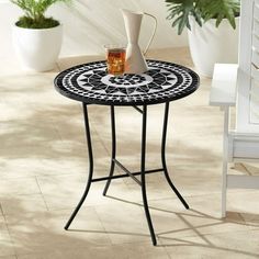 a black and white table sitting on top of a tiled floor next to potted plants