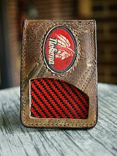 a brown leather wallet with a red and black checkered design on the front, sitting on top of a wooden table