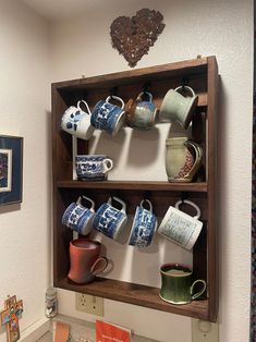 a shelf filled with cups and mugs on top of a counter next to a wall