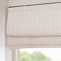 a window with a white roman blind in front of it