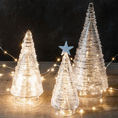 three clear glass christmas trees with white lights