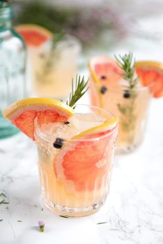 two glasses filled with drinks and garnished with orange slices