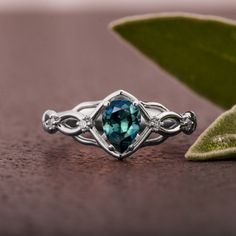 A handmade Celtic style platinum ring set with a beautiful, pear shaped Montana sapphire and small accent diamonds. The center stone is a 5mmX7mm natural Montana teal sapphire of high quality. Please note that the sapphires are natural stones and the exact shade may vary. The smaller stones are natural diamonds with a total carat weight of 0.06ct The ring is made with any of the available metals you select. All of the metals we use are 100% recycled. If you have any questions please feel free to Moissanite Teardrop Promise Ring, Teardrop Moissanite Ring With Center Stone, Teardrop Moissanite Promise Ring, Pear-shaped Topaz Promise Ring With Accent Stones, Pear-shaped Sapphire Ring With Center Stone, Teardrop Promise Ring With Accent Stones, Diamond Teardrop Emerald Ring For Promise, Teardrop Diamond Emerald Ring For Promise, Teardrop Emerald Ring With Diamond Prong Setting