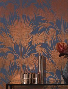 a vase with flowers on a table in front of a wallpapered background that looks like palm trees