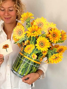 a woman holding a bouquet of sunflowers and a card