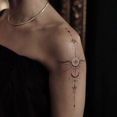 a woman's arm with a tattoo on it that has an arrow and stars