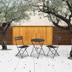 two folding chairs and a table in front of a wooden wall with trees on it