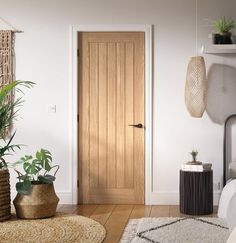 a room with a bed, rugs and plants on the floor next to a wooden door