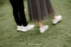 two people in white shoes walking on grass