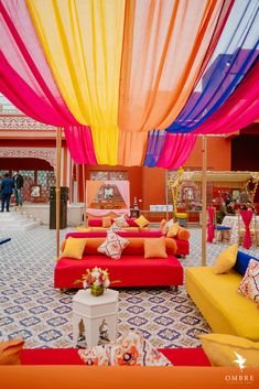 a room filled with lots of different colored couches and tables covered in colorful draping