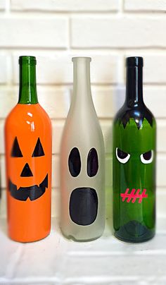 three halloween bottles with faces painted on them