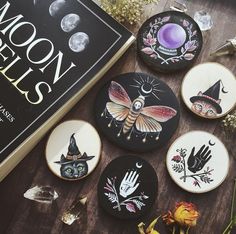 several decorated cookies sitting on top of a table next to a book and some flowers