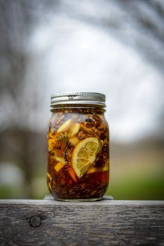 a glass jar filled with food sitting on top of a wooden table next to a tree