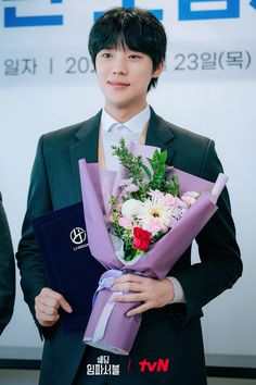 a young man holding a bouquet of flowers in front of a tv advertisement for the korean television