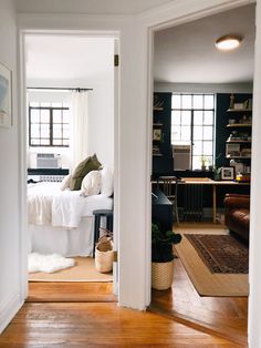 an open door leading to a bedroom with a bed and desk in the background on a hard wood floor