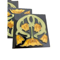 two black and yellow decorative plates with flowers on the bottom one is shaped like a flower