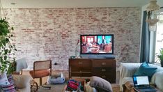 a living room filled with furniture and a flat screen tv sitting on top of a wooden dresser