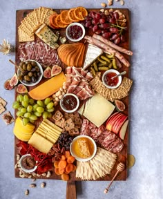 an assortment of cheeses and meats on a wooden platter