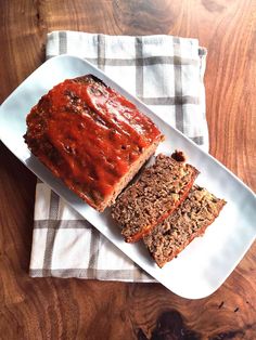 sliced meatloaf on a white plate with two slices next to it and a napkin