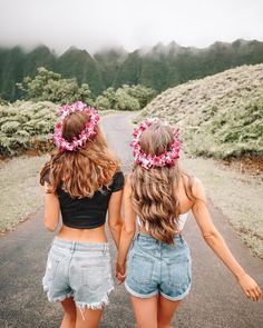 two girls walking down the road holding hands and wearing flower wreaths on their heads