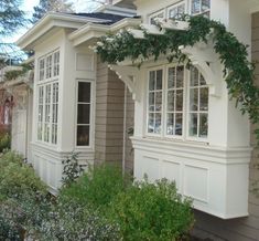 a house with white trim and windows covered in vines