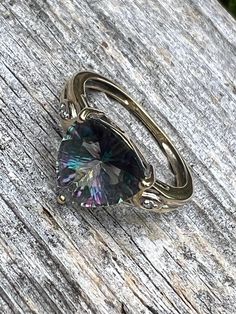 Lots of flash and colour in this lovely 14K yellow gold and trilliant cut mystic topaz ring.   Single diamonds on either side of the topaz offer a bit more subtle sparkle.  The only mark on the band is an R in a circle.  Both diamonds and topaz tested on my gem tester, the gold has been jeweller tested as 14K.  On my mandrel the ring fits to size 6, however, the band is a bit misshapen so I think a more accurate size might be a 6 1/4 or slightly larger.  I try to provide as much information as p Topaz And Diamond Ring, Mystic Topaz Ring, Mystic Topaz, Ring Fit, A Circle, Topaz Ring, Rings Statement, Statement Rings, Topaz