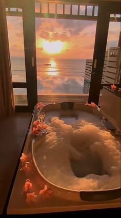 a large bath tub sitting next to a window with the sun setting in the background