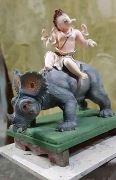 a statue of a baby sitting on top of an elephant