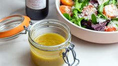 a salad in a jar next to a bottle of mustard