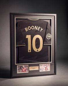 a framed jersey with the number 10 on it is shown in black and gold frame