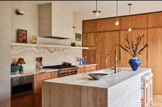 a kitchen with marble counter tops and wooden cabinets, along with an island in the middle