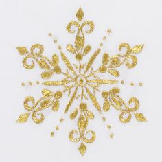 a gold snowflake is shown on a white sheet with golden glitters and leaves