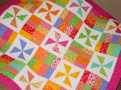 a multicolored quilt is displayed on the floor