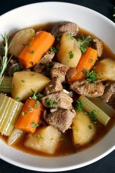 a white bowl filled with stew and carrots on top of a black tablecloth