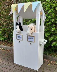 two stuffed animals in a white box on the side of a road next to bushes