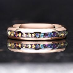 two wedding bands with different colored stones on top of each other, one in gold and the other in white gold