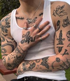 a man with many tattoos on his arms and chest is holding his hands in front of him