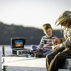 an old man sitting next to a young boy on a boat with a small tv