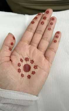 a person's hand with small red flowers on it and dots all over the palm