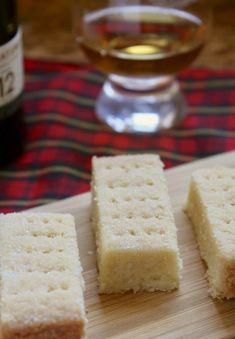 four pieces of bread sitting on top of a wooden cutting board next to a bottle of wine