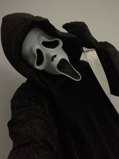 a person wearing a mask with a knife in their hand and a black robe around his neck