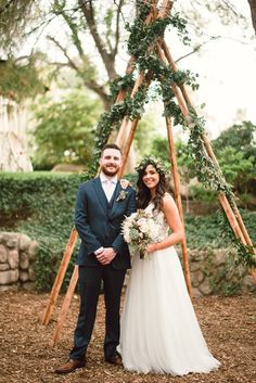 a bride and groom pose for a photo in front of an arbor