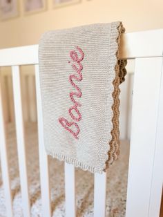 a crocheted blanket hanging from the side of a white crib in a nursery