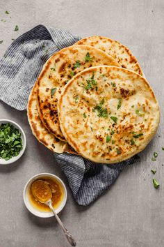 three flatbreads with sauce and herbs on the side