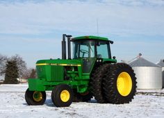 a large green tractor parked in the snow