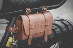 a brown leather bag sitting on the back of a motorcycle