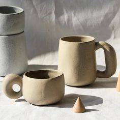 three different shapes and sizes of mugs sitting on a table next to each other