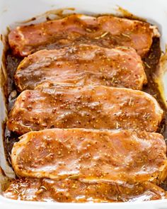 three pork chops covered in gravy in a white casserole dish